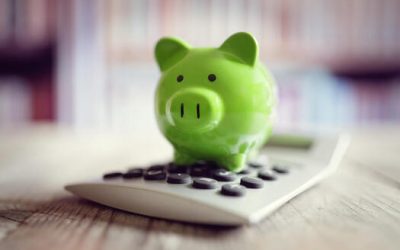 a green piggy bank on-top of a calculator